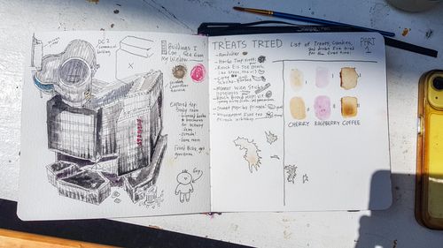 Open sketchbook showing a pen-and-ink drawing of an angular building and watercolor swatches with handwritten notes