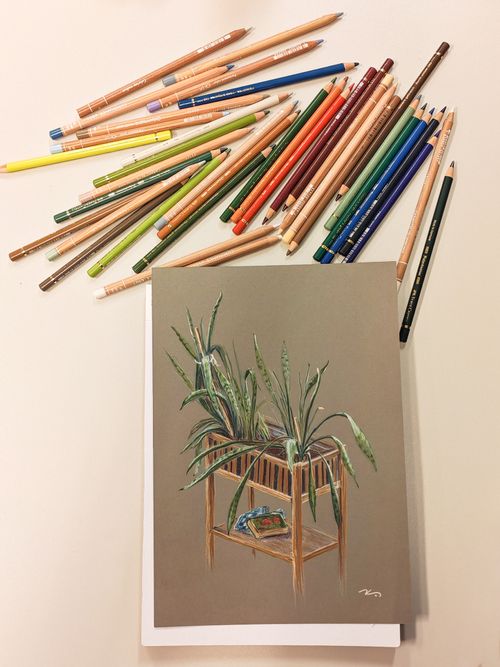 A student drawing with charcoal at a studio worktable.